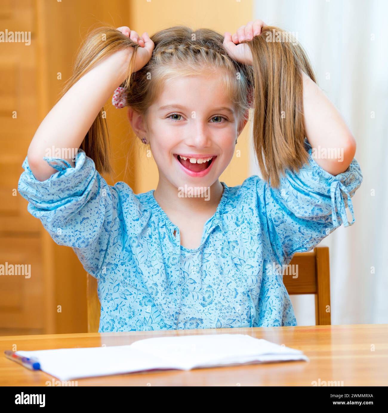 Funny little girl studying at home and smiling Stock Photo - Alamy