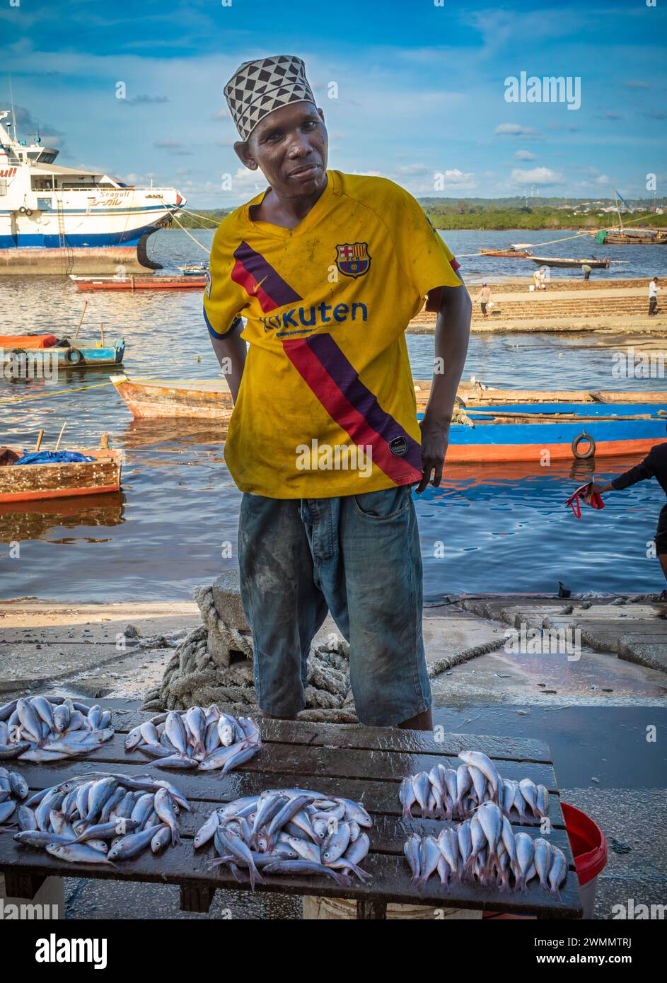 A fisherman sells fish on the quayside at Darajani Market, or the fish market, in Stone Town, Zanzibar, Tanzania. Stock Photo