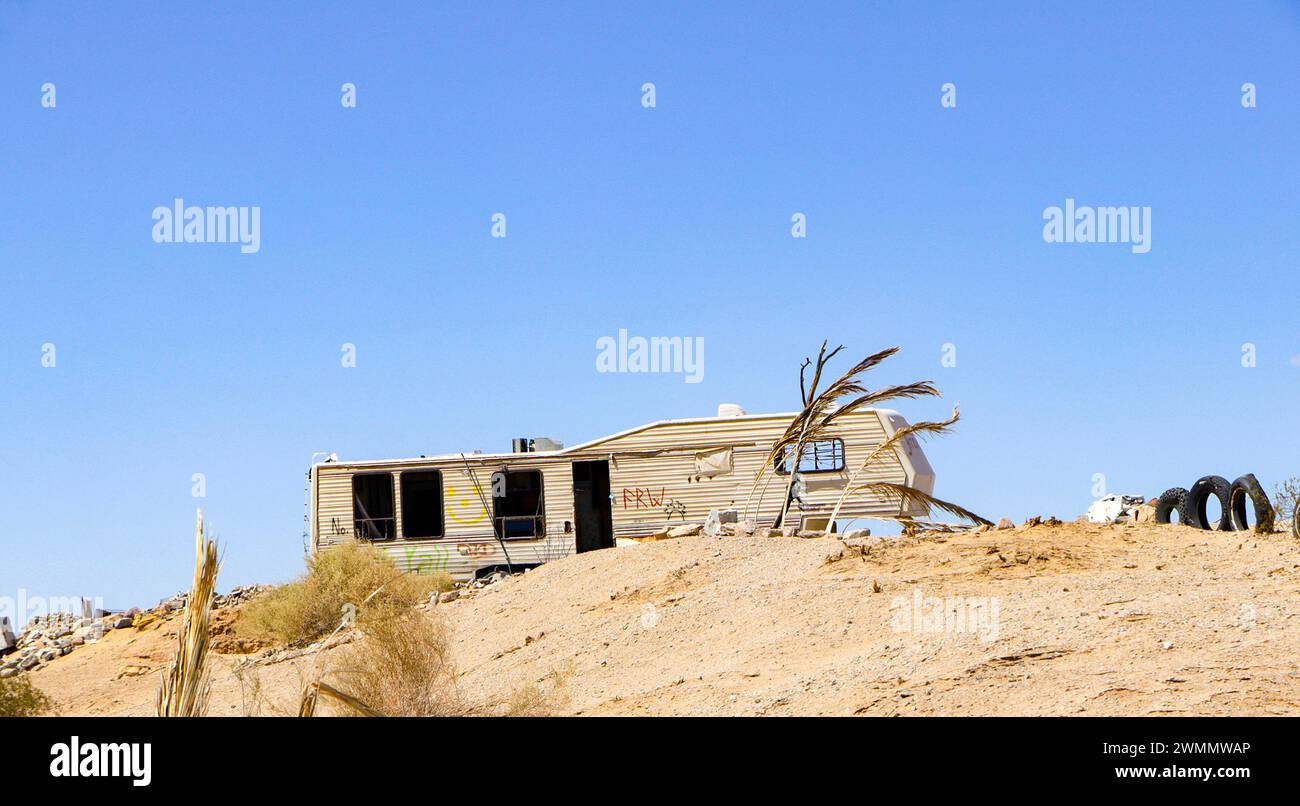 Abandoned, dilapidated motorhome on a barren desert landscape under a clear blue sky. Stock Photo
