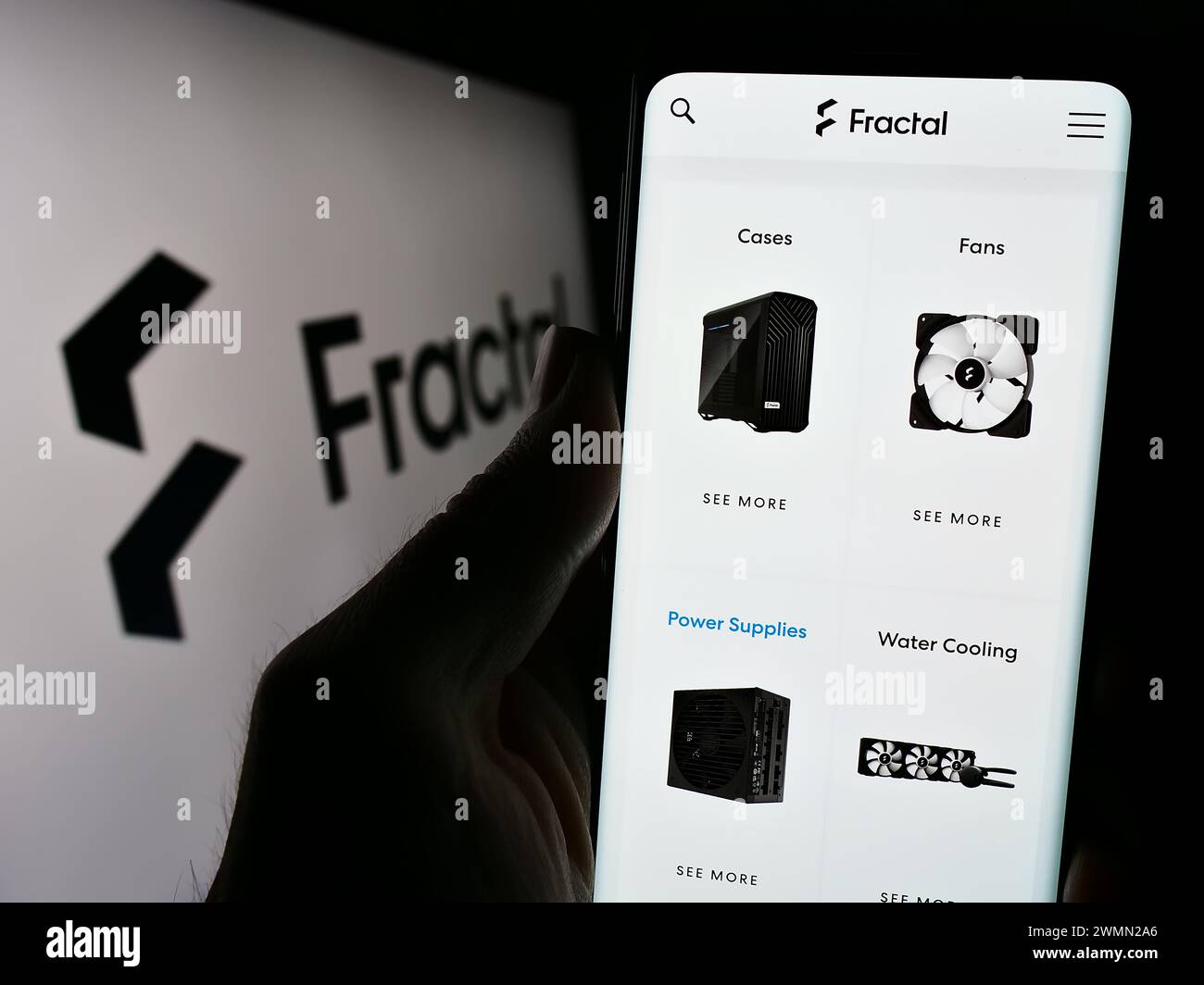 Person holding cellphone with webpage of Swedish computer hardware design company Fractal Gaming AB with logo. Focus on center of phone display. Stock Photo