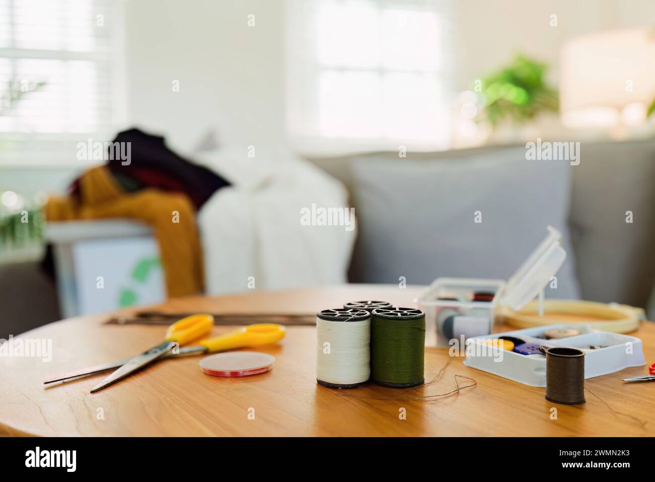 Spools of thread and basic sewing tools including pins, needle, a thimble, and tape measure Stock Photo