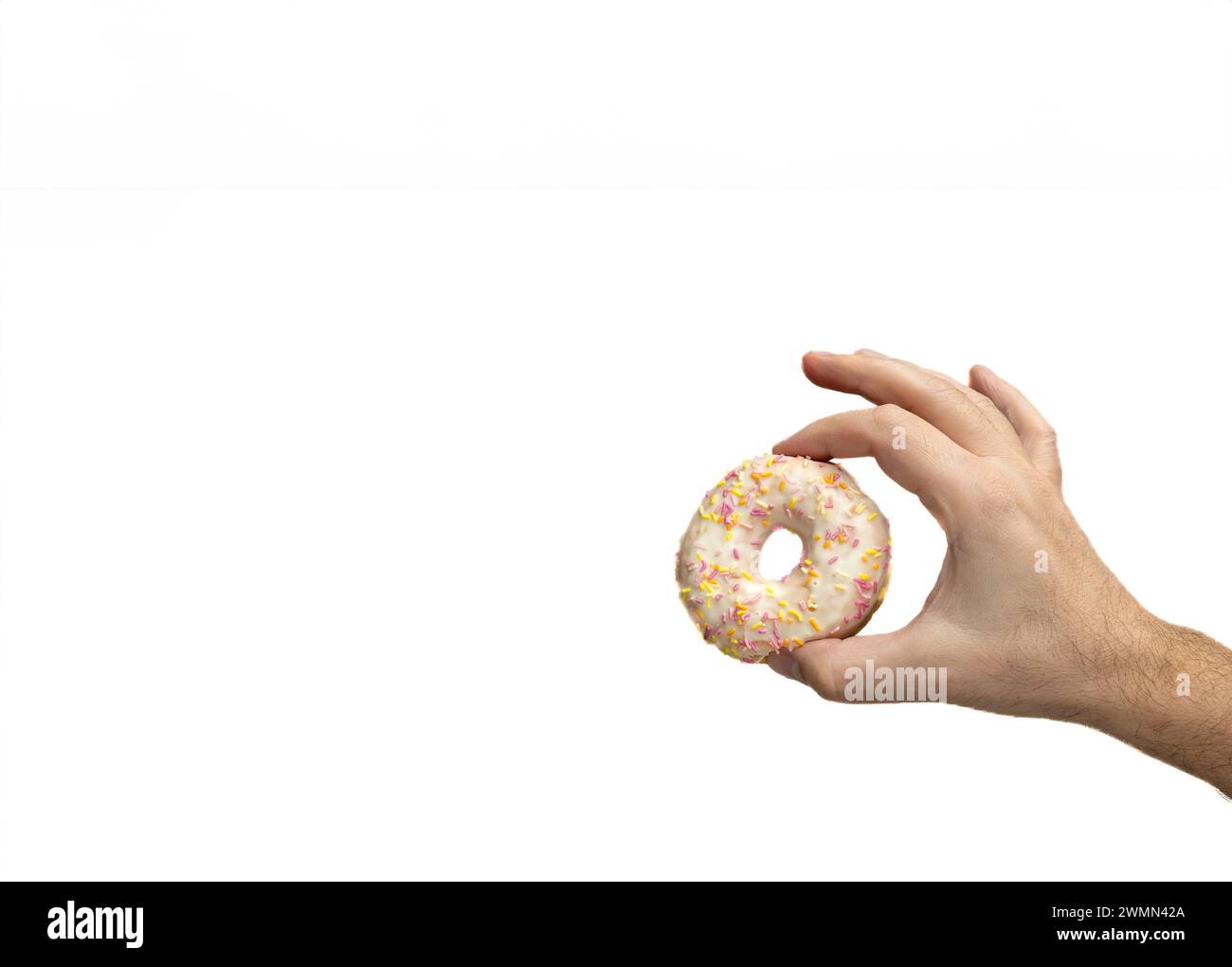 Round donut with frosting and colored sprinkles held between Caucasian man's fingers. Isolated on white. Stock Photo