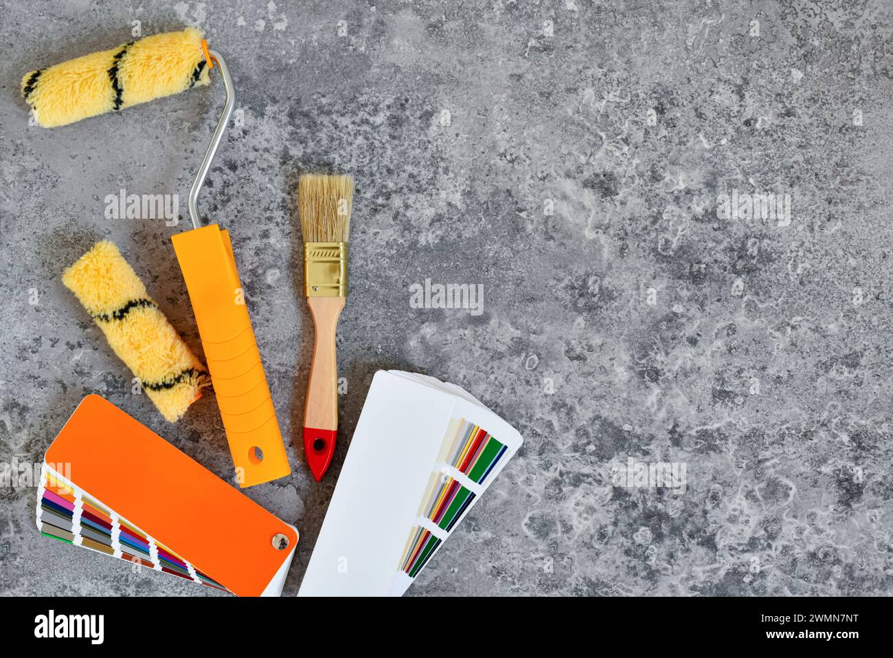 Home paint roller and a paint brushe, color swatches on gray stone background. Top view. Repair housing concept. Stock Photo