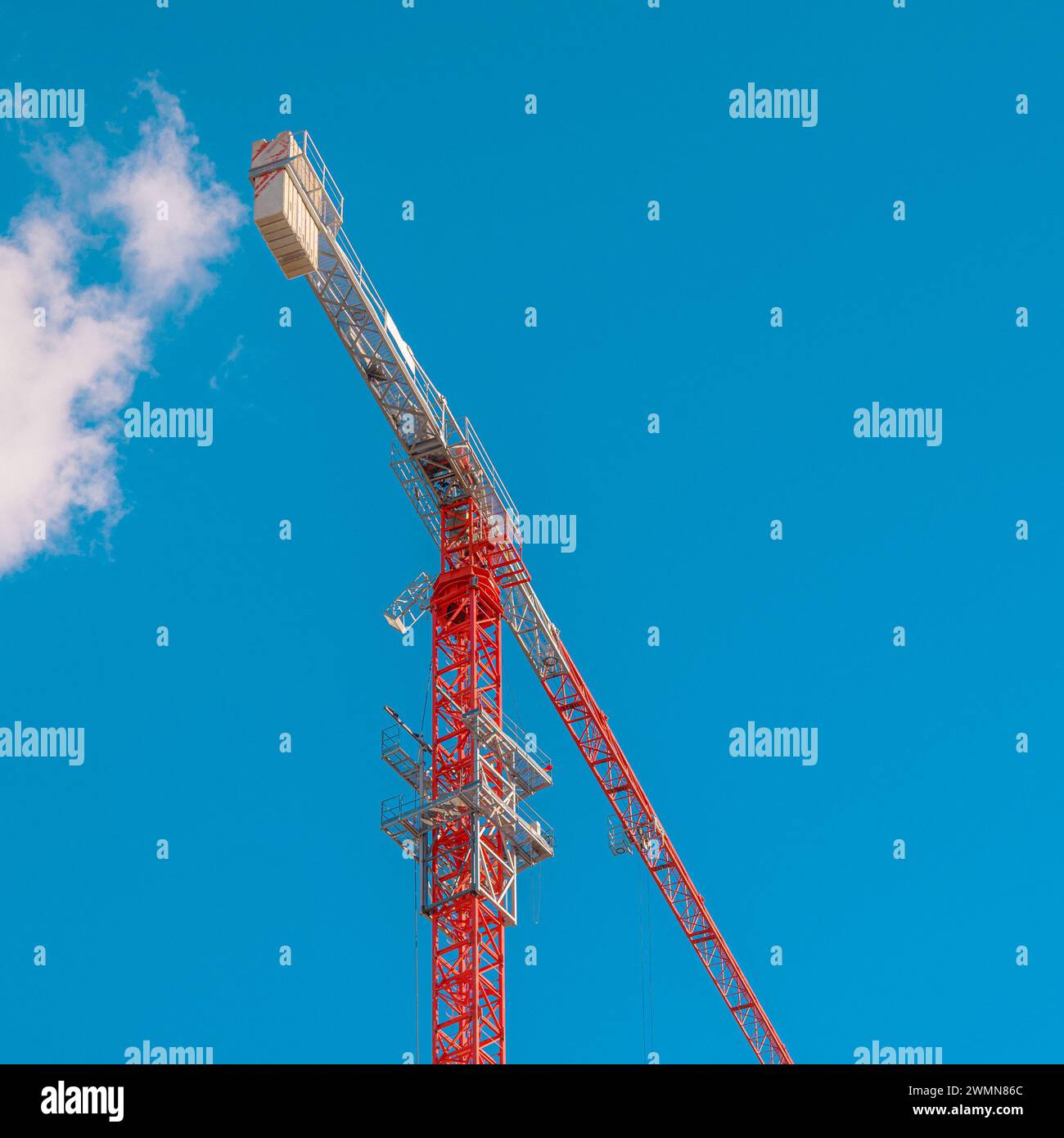 A red construction crane against sky with cloud entering it. Stock Photo