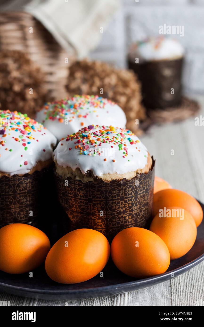 Closeup of glaze decorated Easter cakes and yellow colored eggs on a plate. Stock Photo