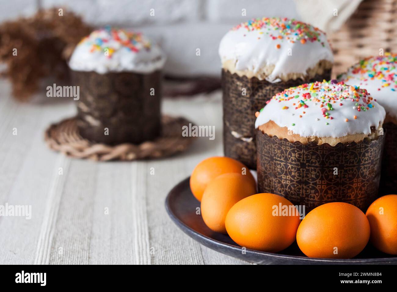 Glaze decorated Easter cakes and orange colored eggs on a plate closeup. Stock Photo