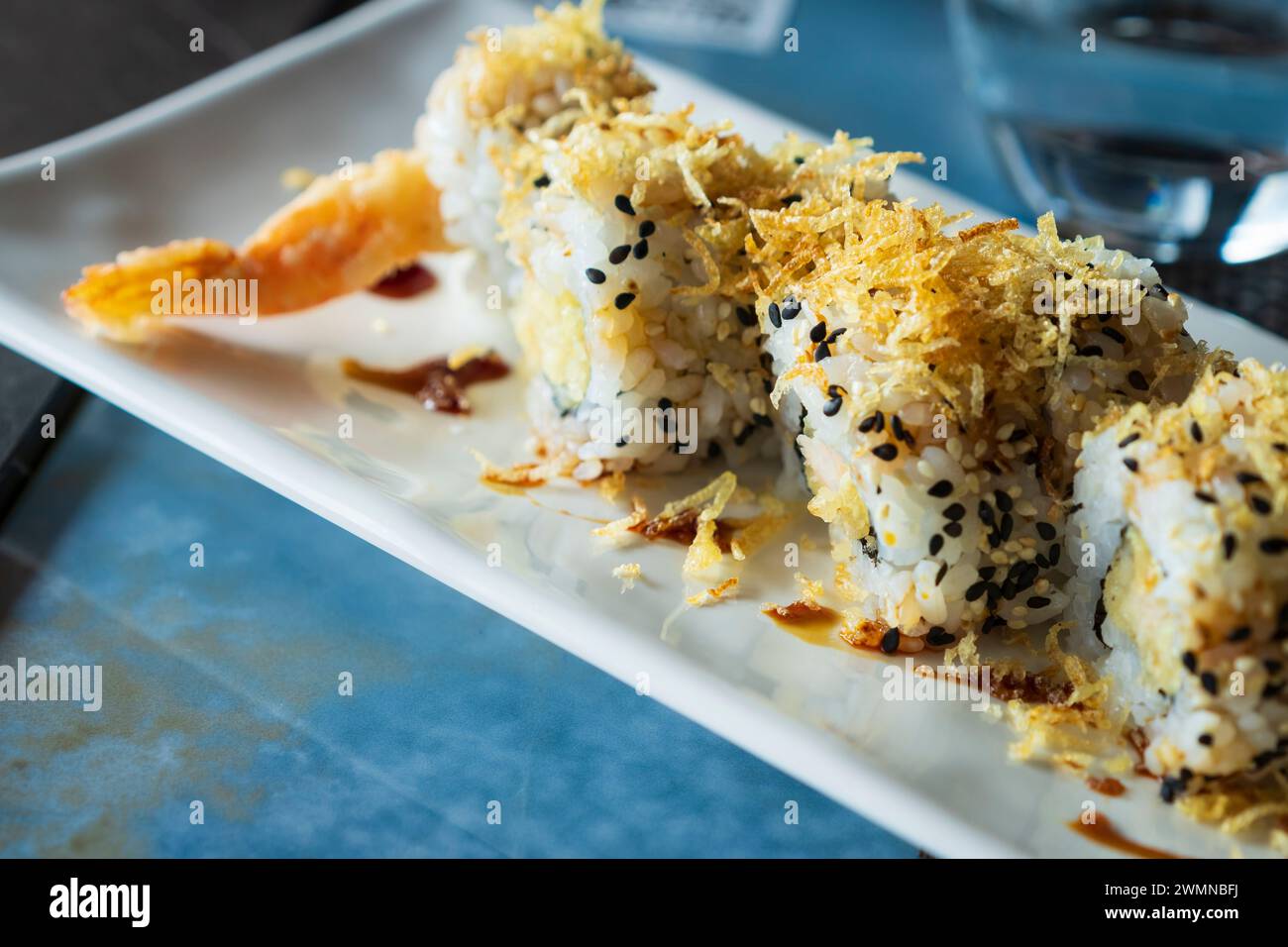Unagi ebi ten roll, close up view.sushi set with shrimp in tempura, oshinko, garnished with edible flower and black sesame, on an oriental tray, plate Stock Photo