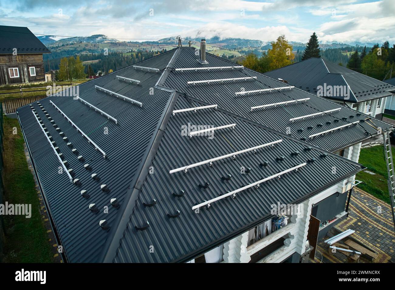 Preparing for installation on roof of wooden house in mountains. Solar ... - Off-Grid Building Envelope Roof Installation