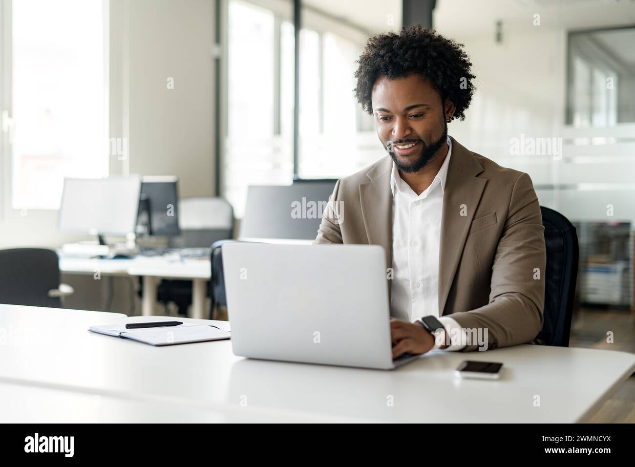 Confident and approachable African-American businessman sits at his ...