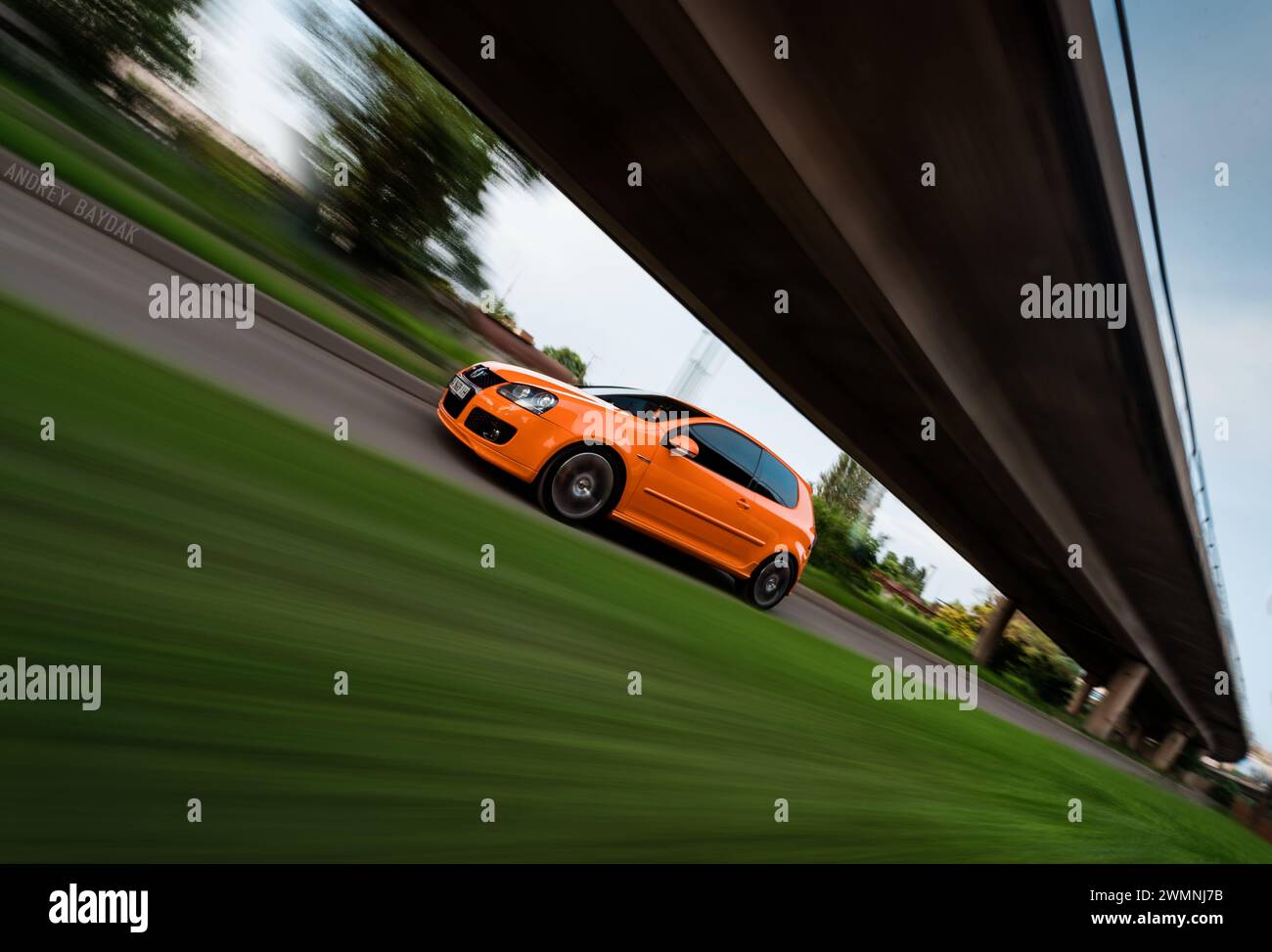 motion shot of orange Volkswagen Golf GTi mk5. Driving fast on narrow road. Stock Photo