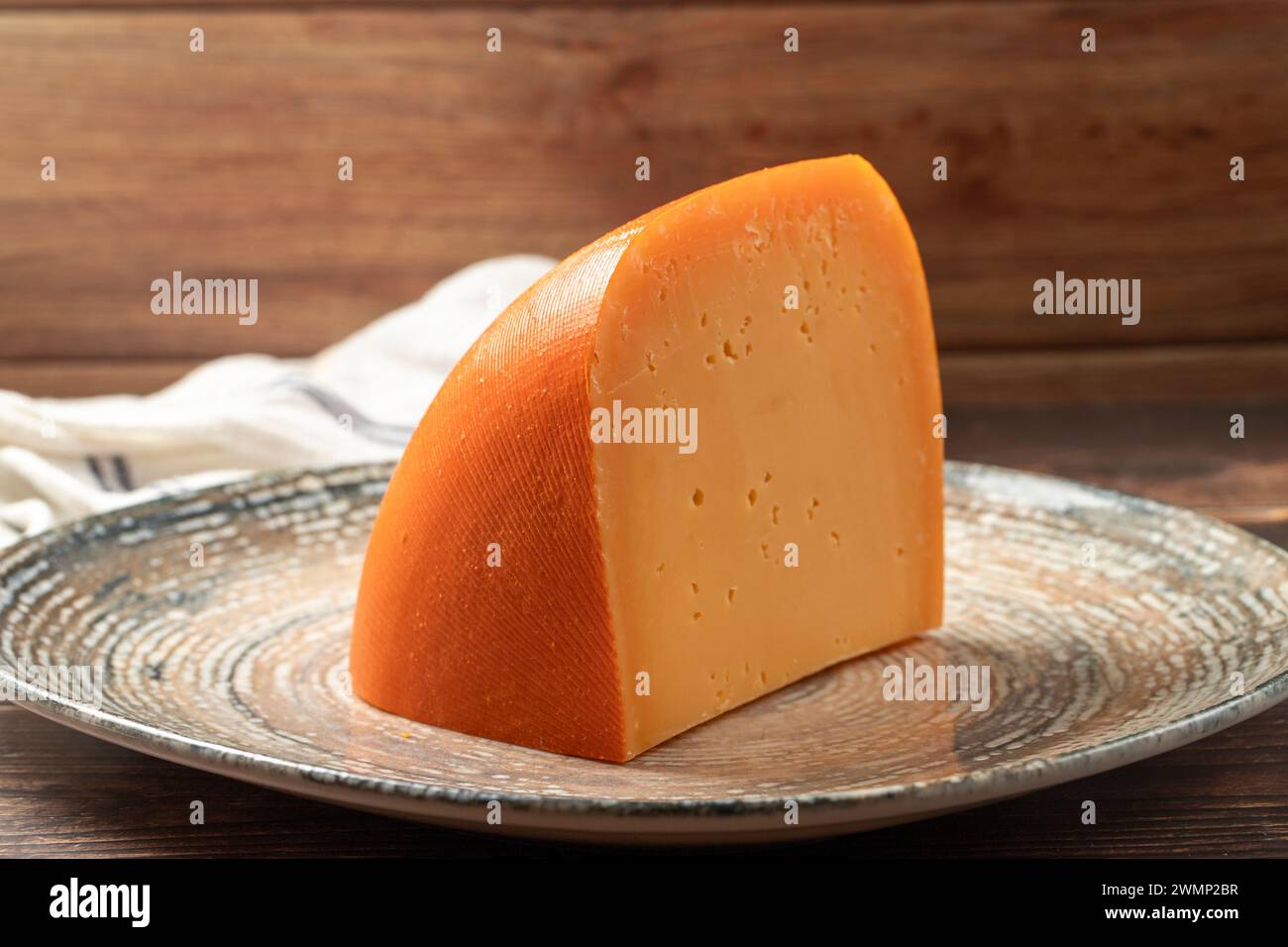 Mimolette cheese. Dairy products. Slices of Mimolette cheese on a plate Stock Photo