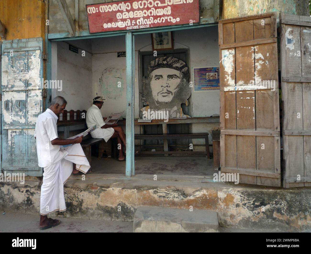 India, kerala, Kochi: Indian men read the newspaper in a public office of the Communist Party of Kerala with the image of Che Gevara Stock Photo
