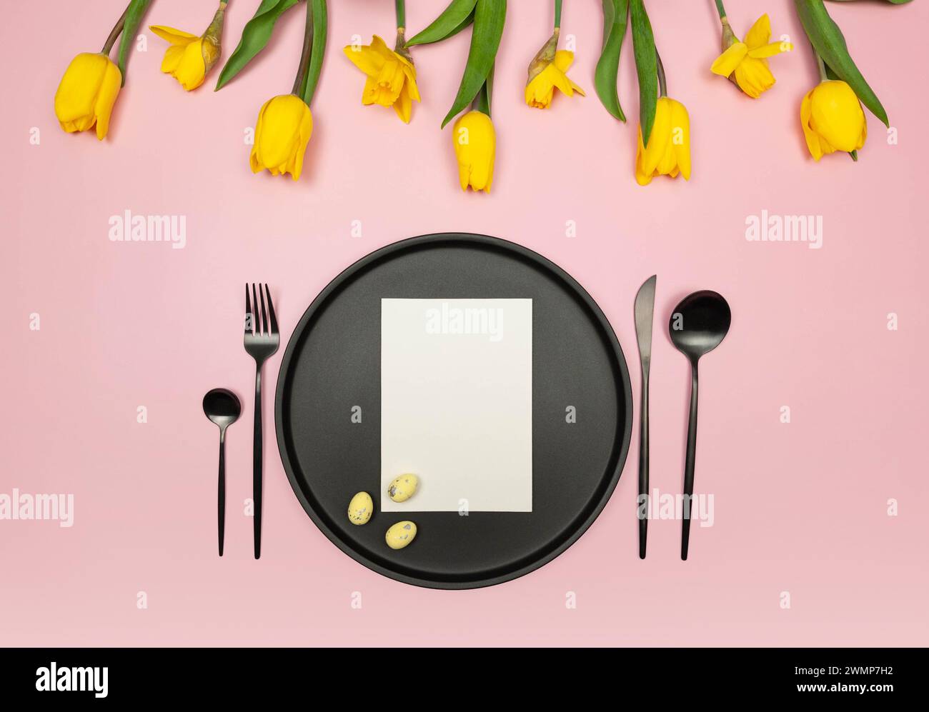 Top view of yellow tulips, daffodils, easter eggs on pink background ...