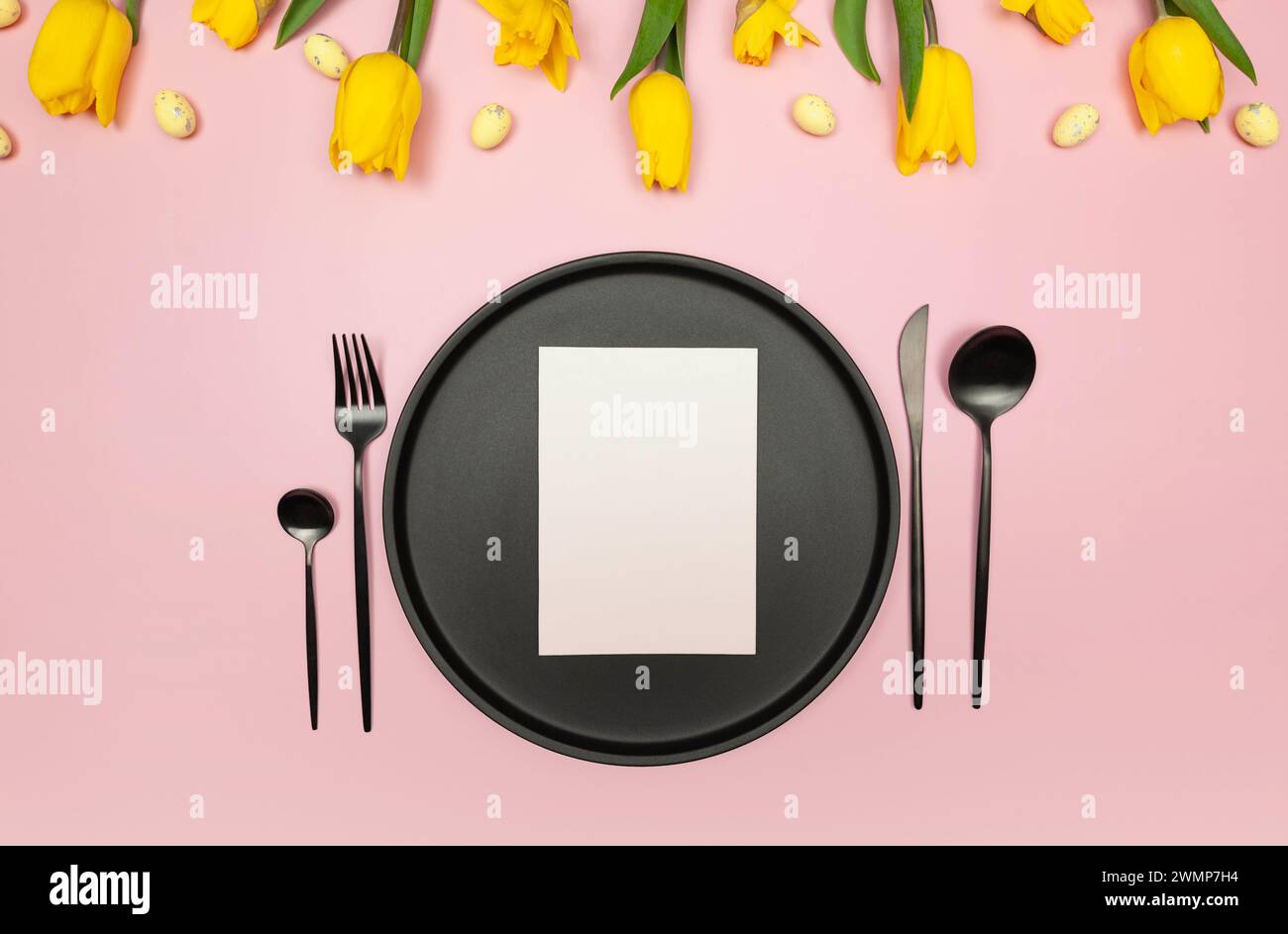 Top view of yellow tulips, daffodils, easter eggs on pink background ...