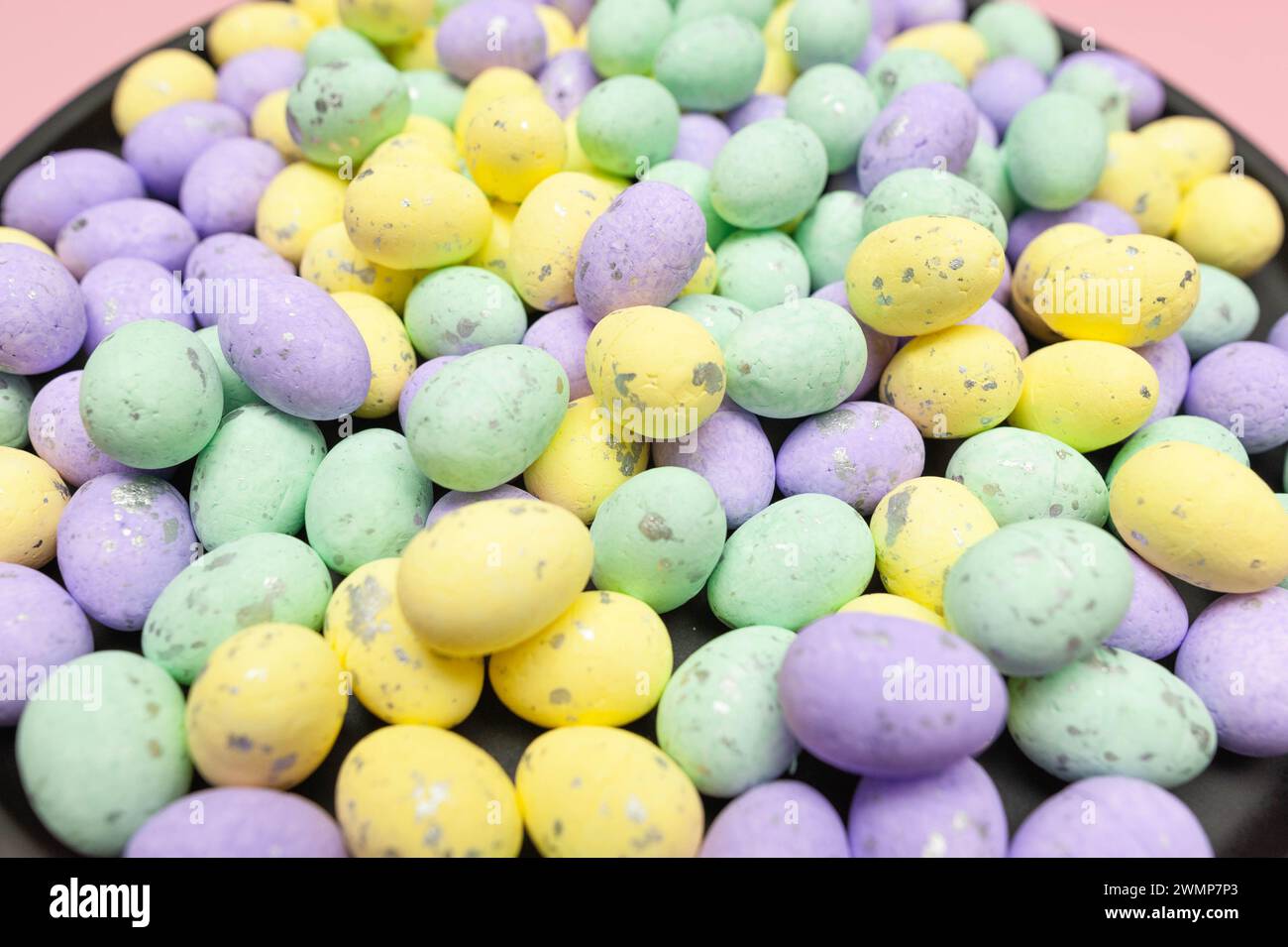 Colourful easter eggs in black plate on pink background. Creative easter composition, spring, copy space. Stock Photo