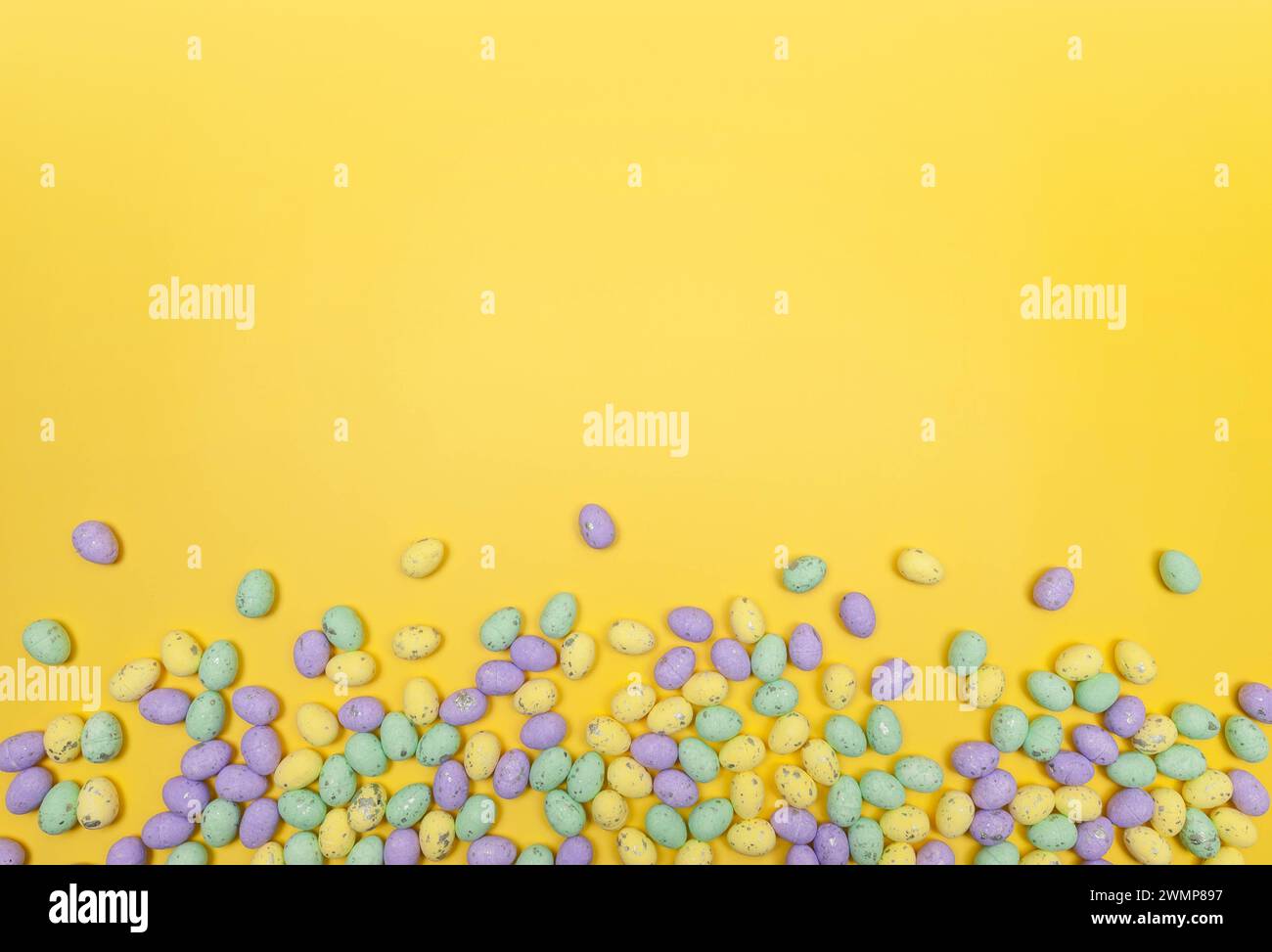 Top view of colourful easter eggs on yellow background. Creative easter composition, spring, copy space, flat lay. Stock Photo