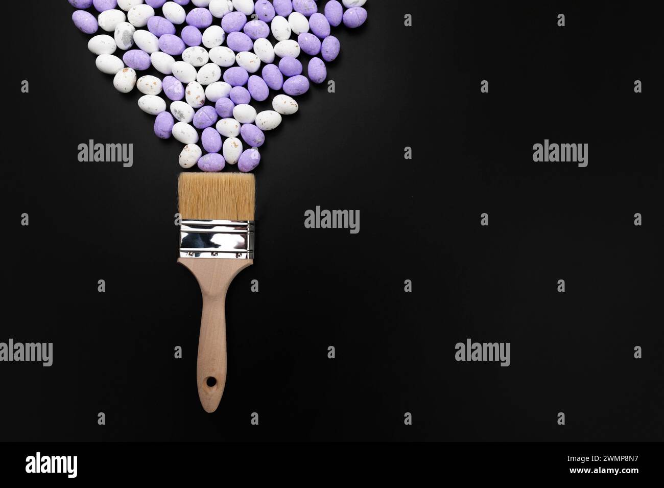 Top view of white and purple easter eggs, paint brush on black background. Creative easter composition, spring, flat lay, copy space. Stock Photo