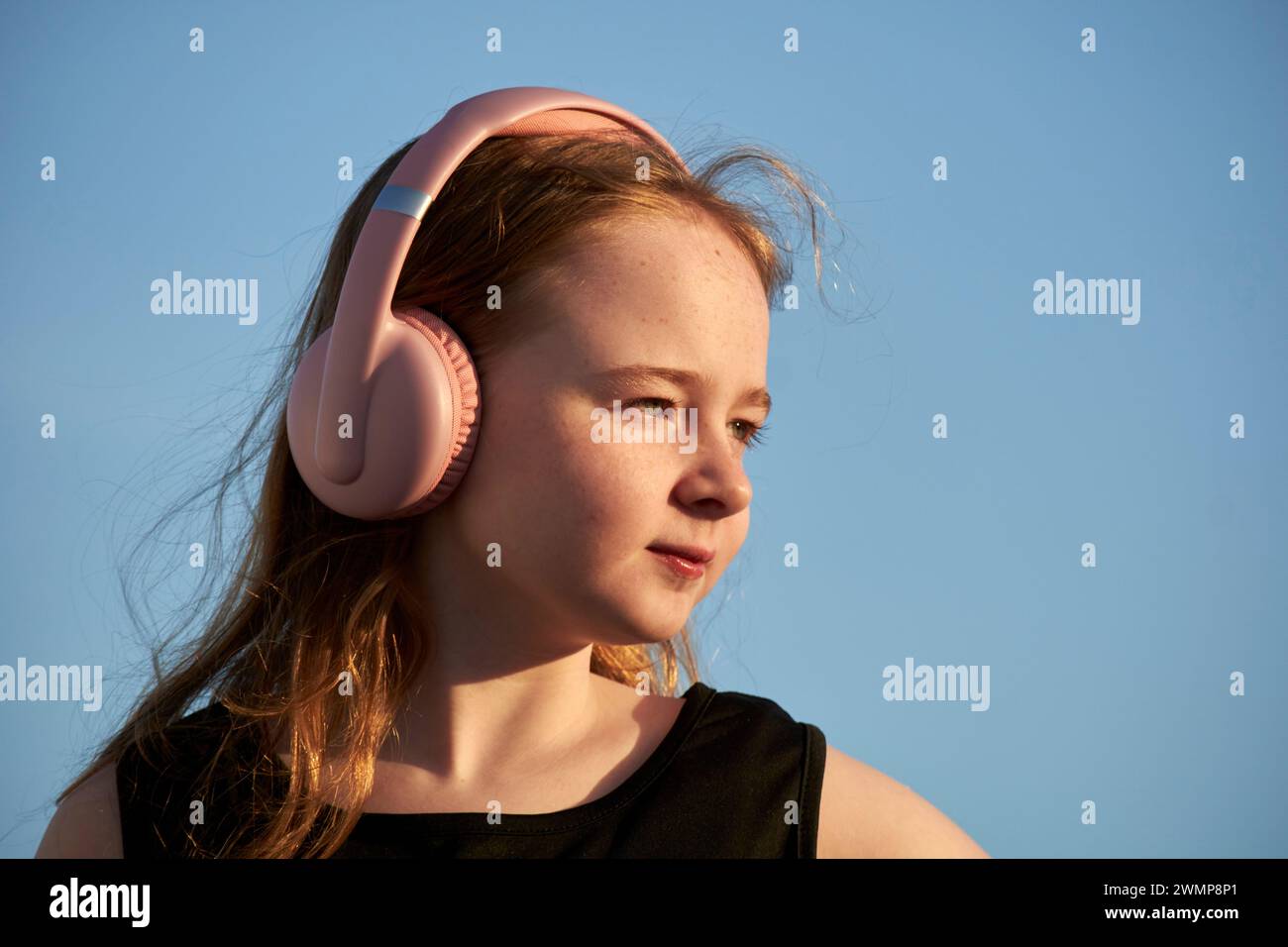 young 10 year old girl wearing headphones looking off at sunset Lanzarote, Canary Islands, spain Stock Photo