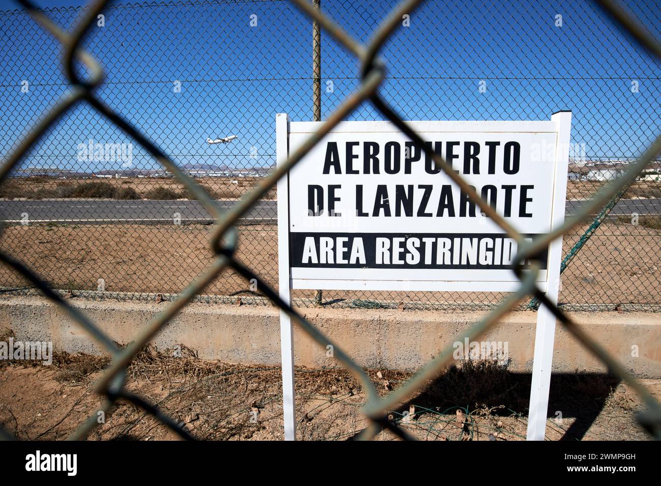 restricted area sign on perimeter fence at ace arrecife airport with aircraft taking off Lanzarote, Canary Islands, spain Stock Photo