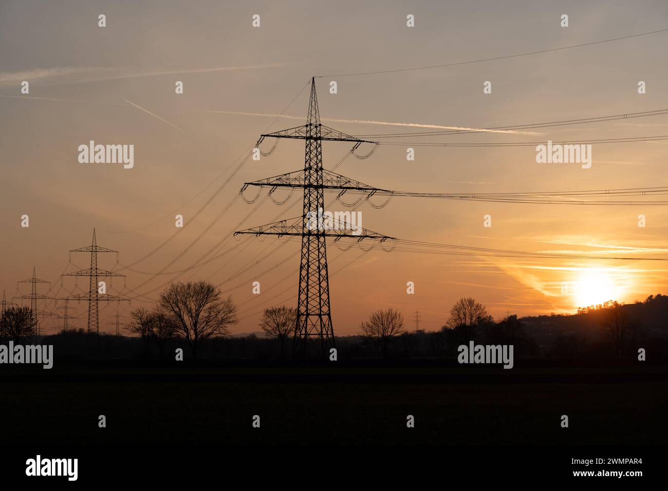 The silhouetted power lines in rural area at sunset in Giessen, Germany Stock Photo