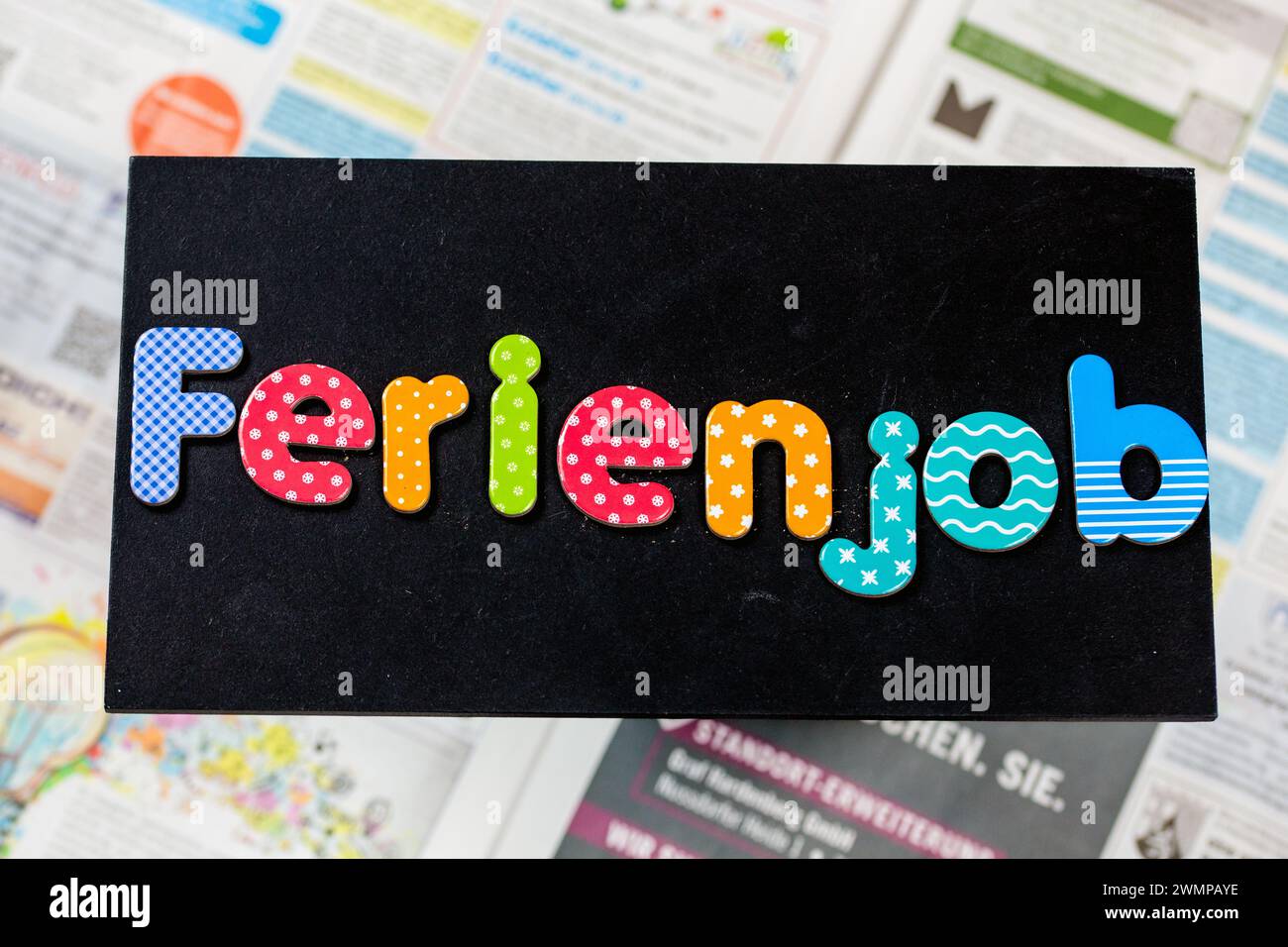 Symbol image of a holiday job: board with the german inscription FERIENJOB in front of the job adverts in a newspaper Stock Photo