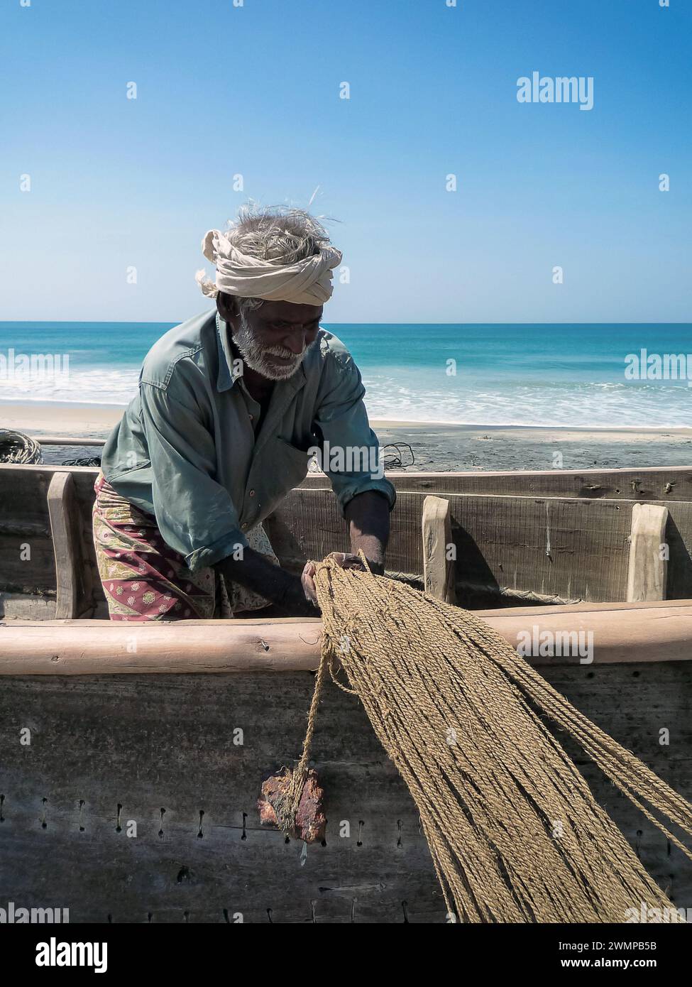 India, Kerala, Varkala: an Indian fisherman rewinds a fishing net on the beach of Varkala Stock Photo
