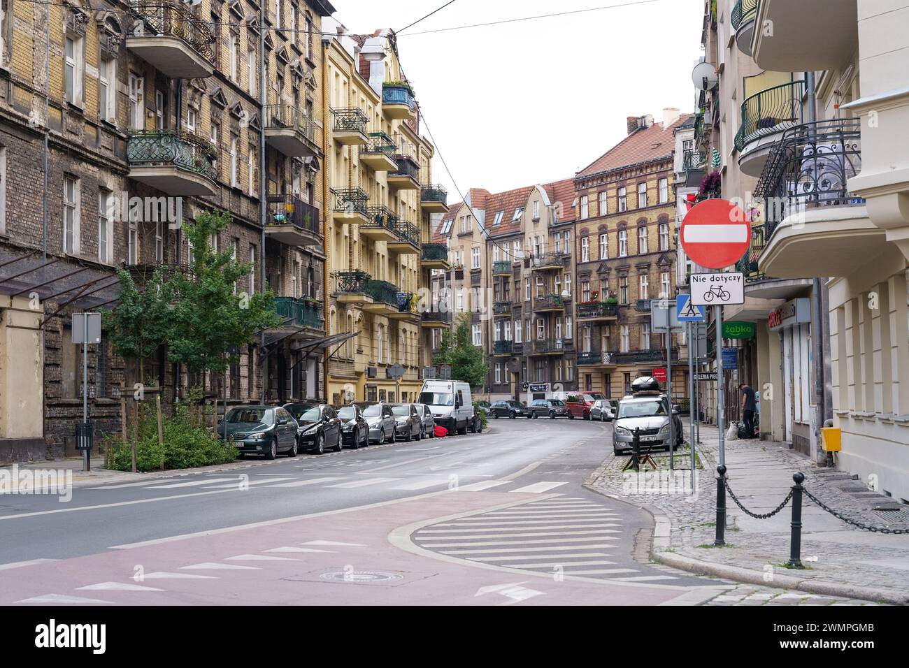 Poznan, Poland - June 18, 2023: A city street lined with parked cars on both sides, creating a busy urban scene. Stock Photo