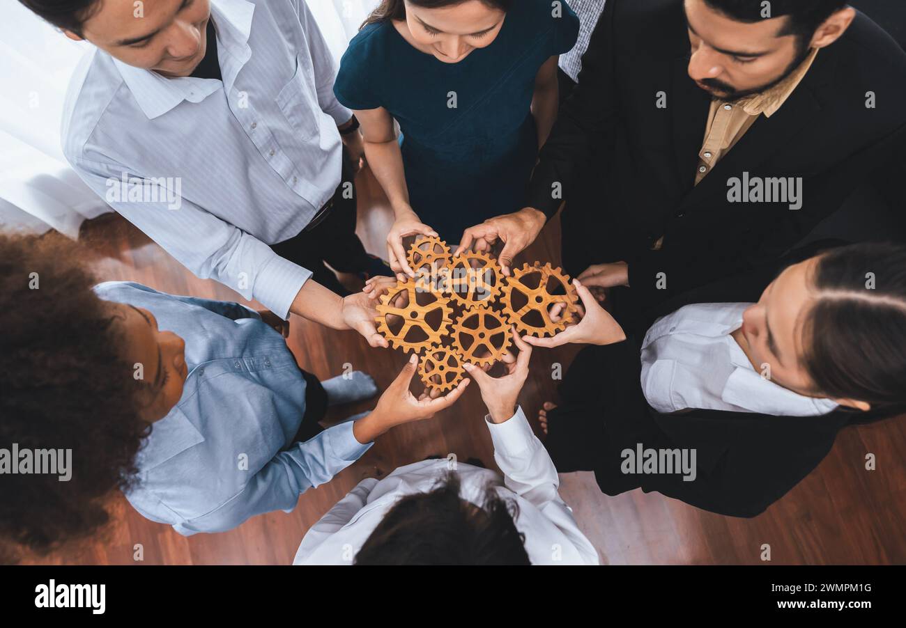 Office worker holding cog wheel as unity and teamwork in corporate ...