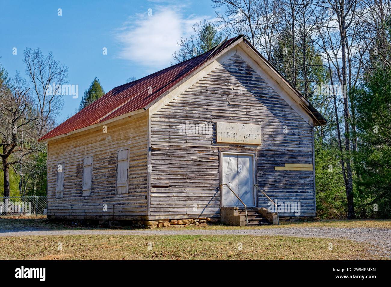 An old church in the mountains on a rural dirt road with a cemetery in the back a wooden building with a metal roof no longer used but being preserved Stock Photo