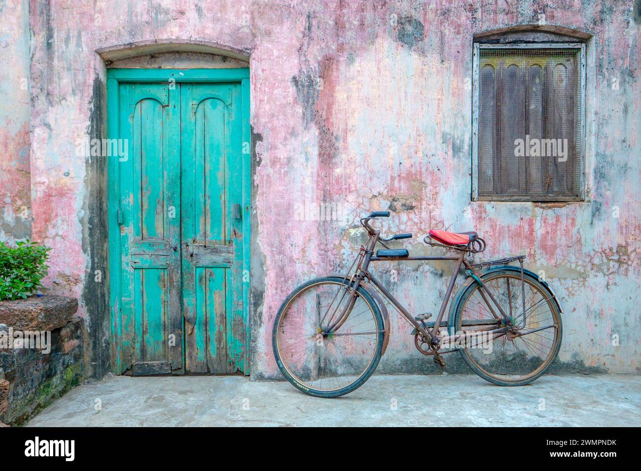 A bicycle propped up outside a colourful entrance to an Indian house Stock Photo