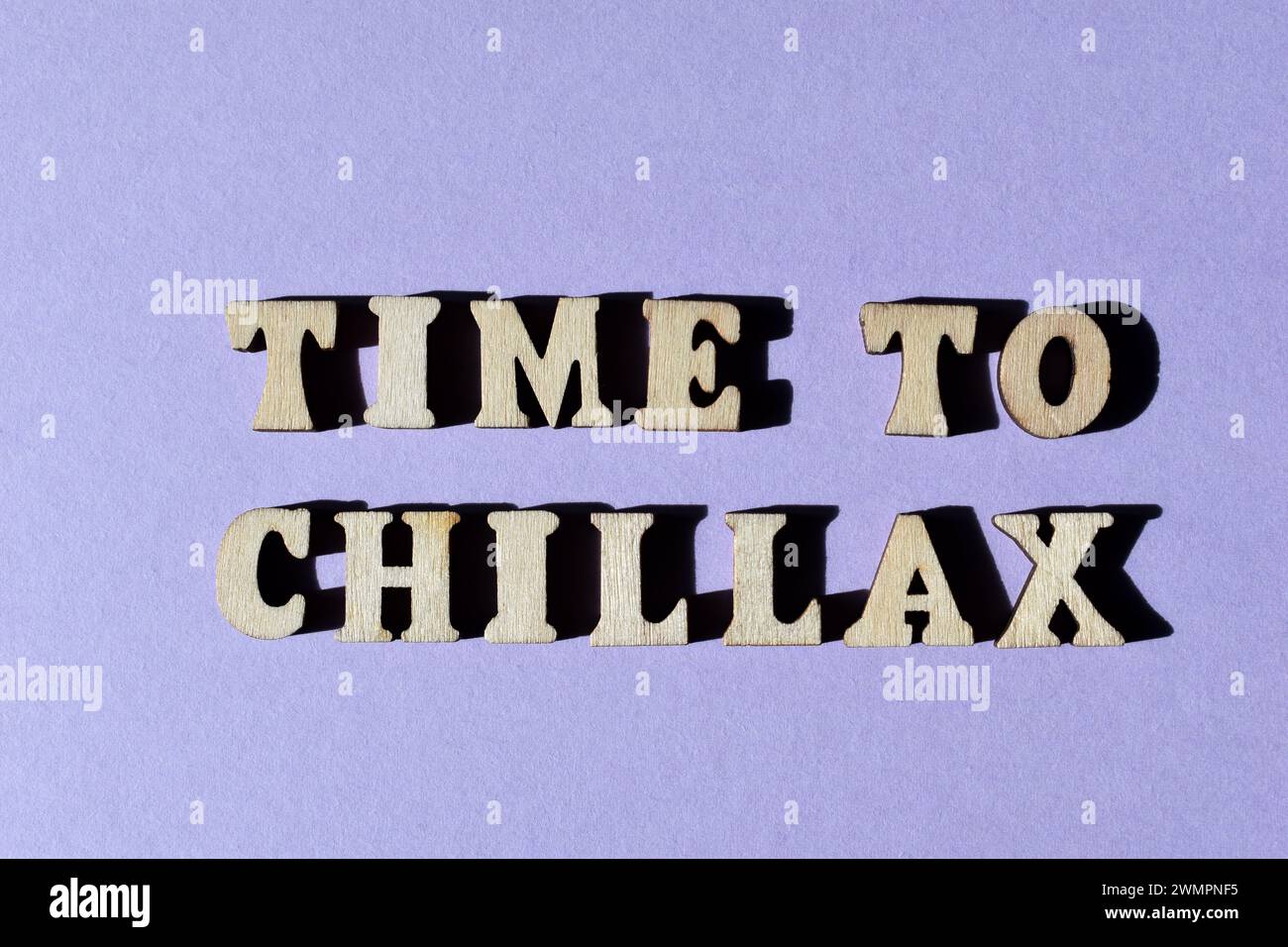 Time To Chillax, a word combination of Chill and Relax, known as a portmanteau, in wooden alphabet letters isolated on purple background Stock Photo