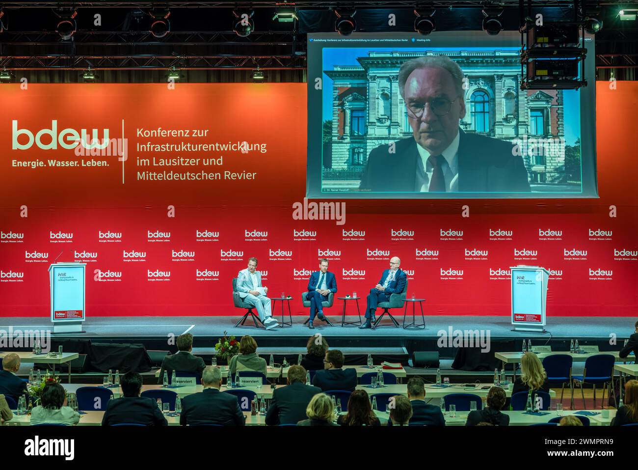 27 February 2024, Brandenburg, Cottbus: Reiner Haseloff (CDU, above), Minister President of Saxony-Anhalt, Dietmar Woidke (SPD, right), Minister President of Brandenburg, and Michael Kretschmer (CDU, center), Minister President of the Free State of Saxony, discuss with moderator Marco Seiffert at the Third Conference on Infrastructure Development in the Lusatian and Central German Mining Region. The conference is being organized by the Central German regional group of the German Association of Energy and Water Industries, which represents around 2,000 companies in the energy supply, drinking w Stock Photo