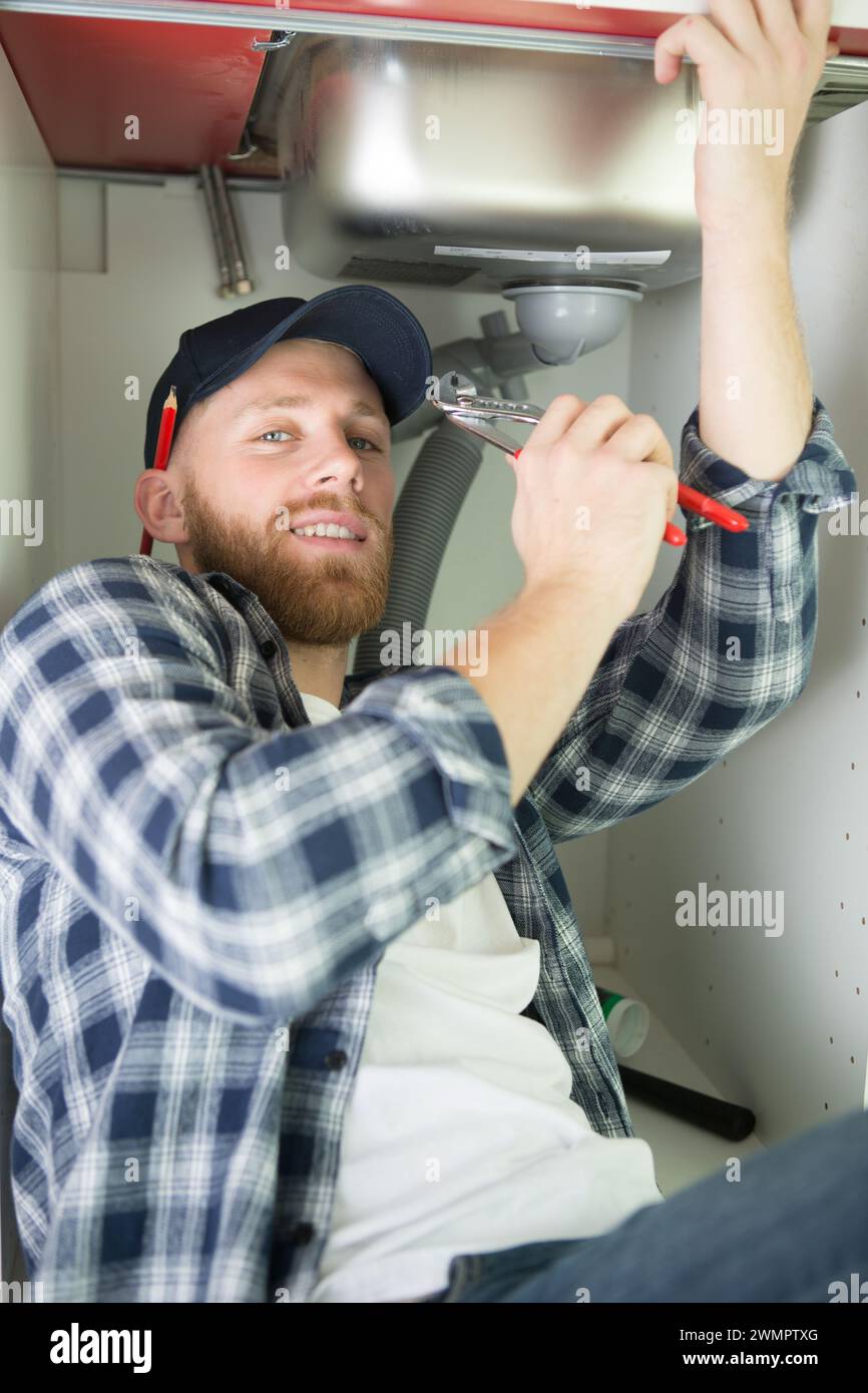 young man fixing a leaky pipe under the sink Stock Photo Alamy
