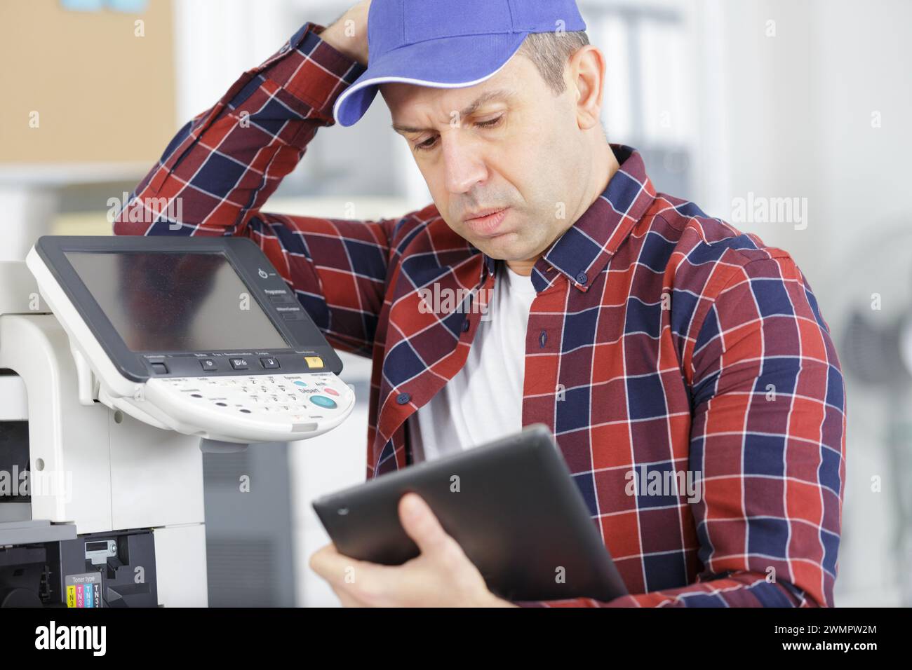 technician using a tablet to fix a printer Stock Photo