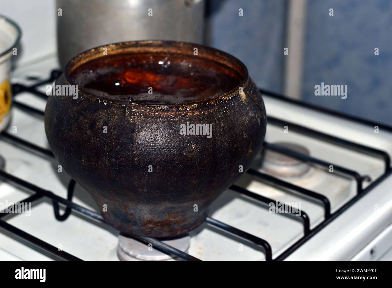 The picture shows an old cast iron pot on a gas stove, vegetables are being boiled. Stock Photo