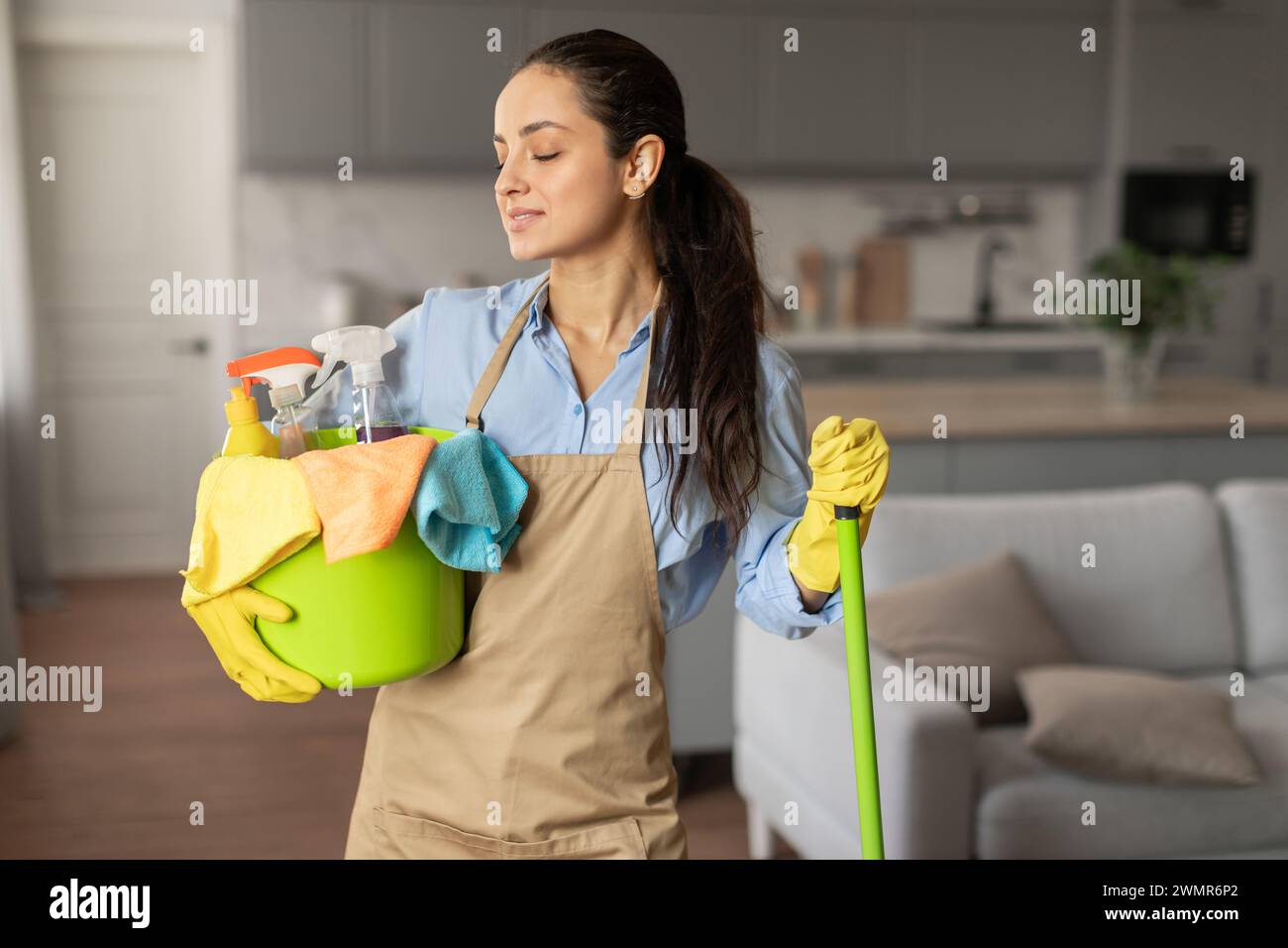 Content woman with cleaning equipment ready for chores Stock Photo