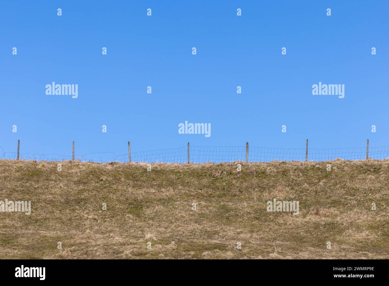 Fence on topp of grassy hill with clean blue sky background Stock Photo ...