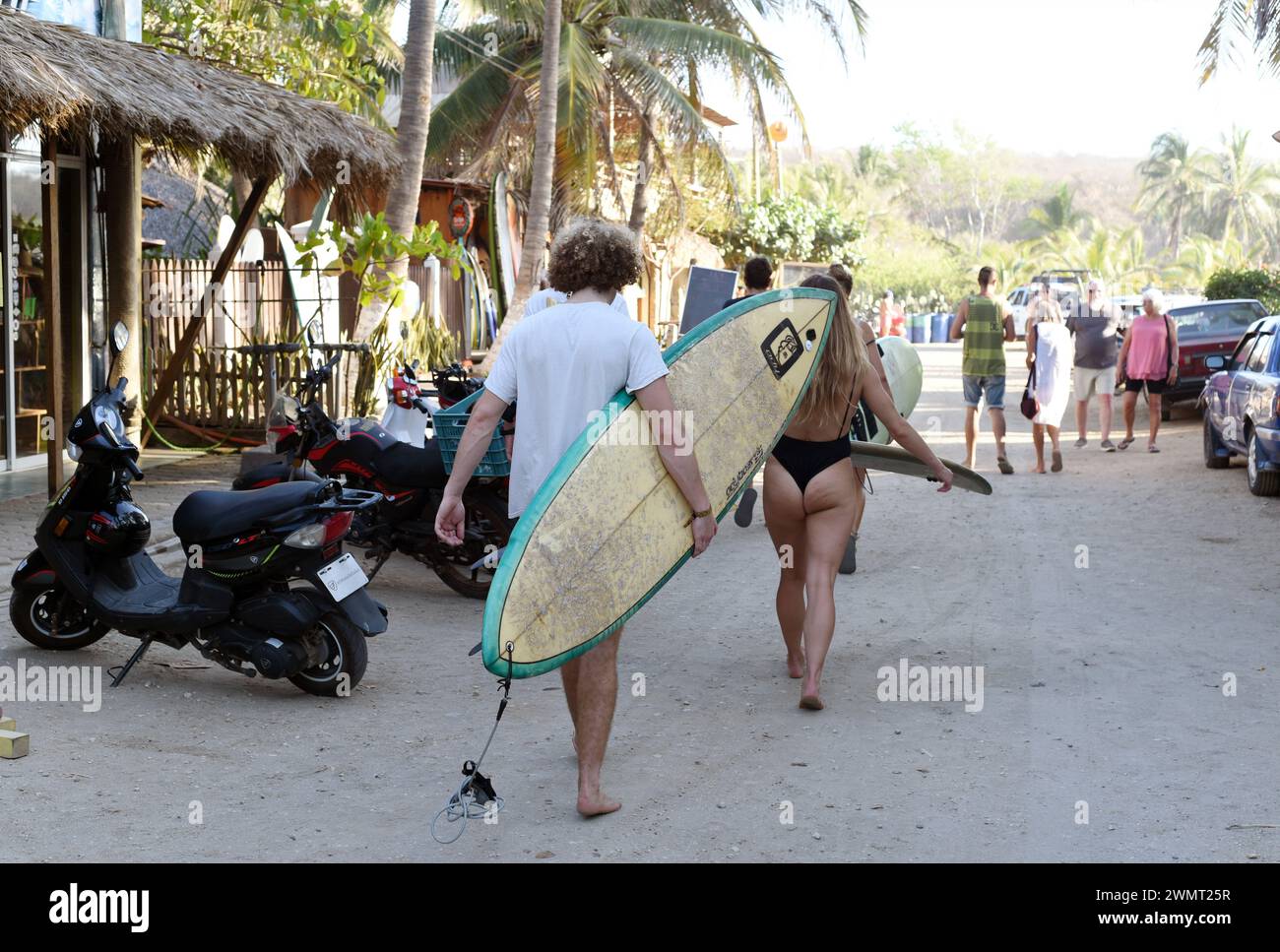 Surfers carry a surfboards while walking through the La Punta area in Puerto Escondido, Oaxaca, Mexico Stock Photo