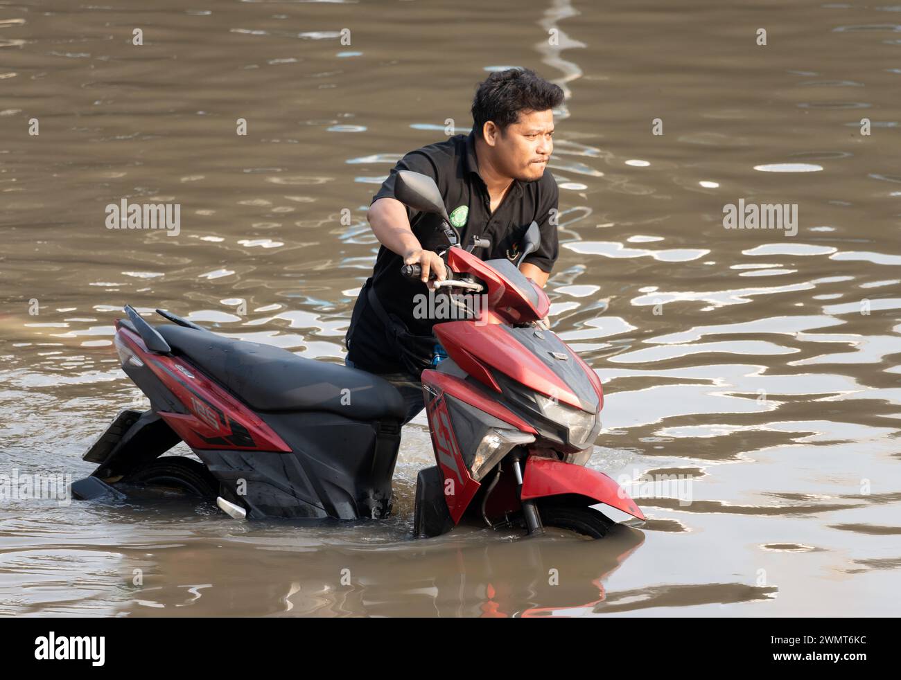 SAMUT PRAKAN, THAILAND, FEB 11 2024, A man pushes a motorbike through a