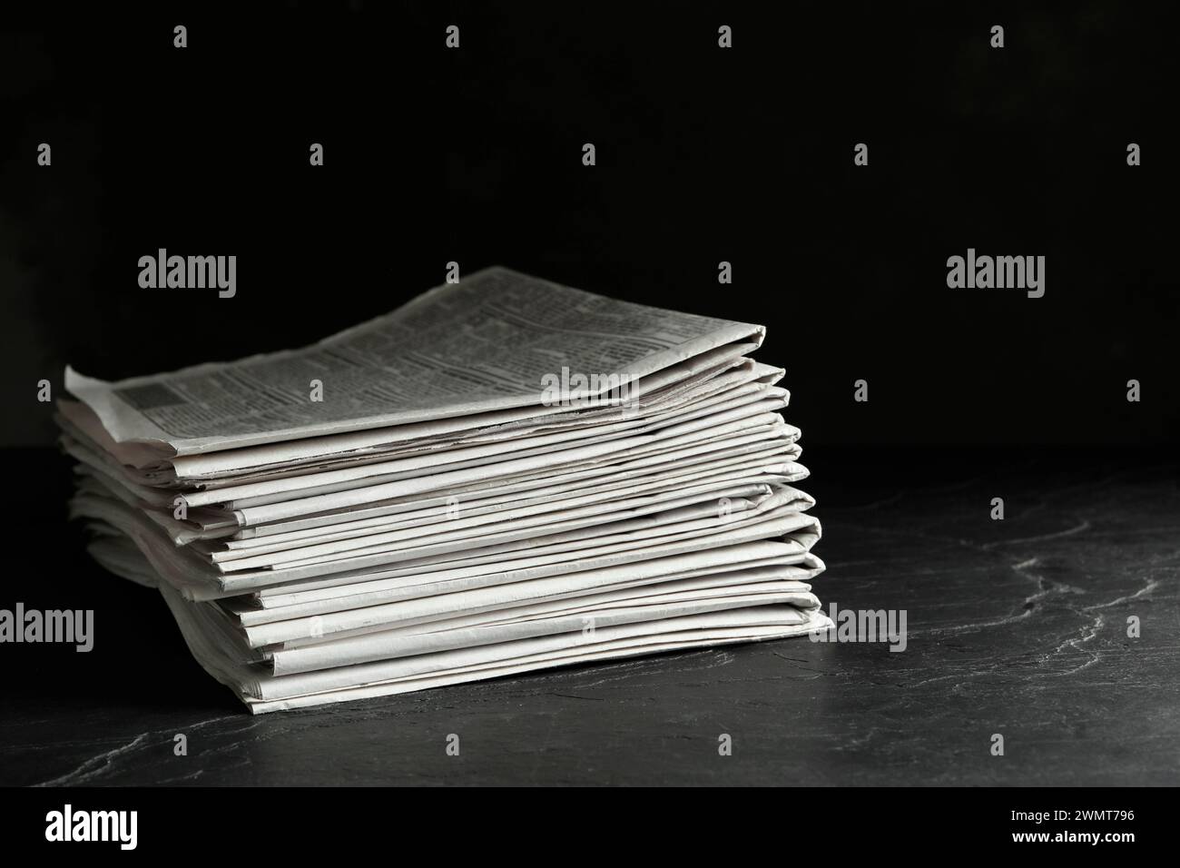Stack of newspapers on dark stone table. Journalist's work Stock Photo