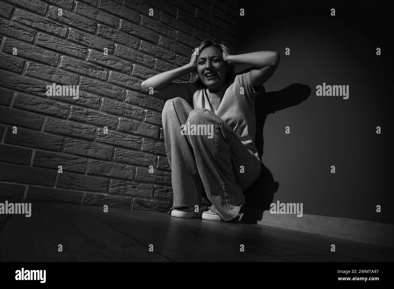 Scared mature woman sitting in corner Stock Photo - Alamy