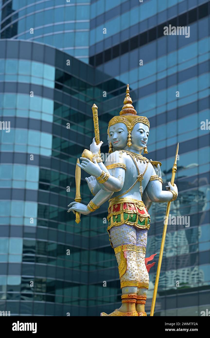 A blue gold statue of Jatulokbal, a composite Thai iconography of the Lokapalas, defending the four cardinal directions, set against skyscrapers Stock Photo