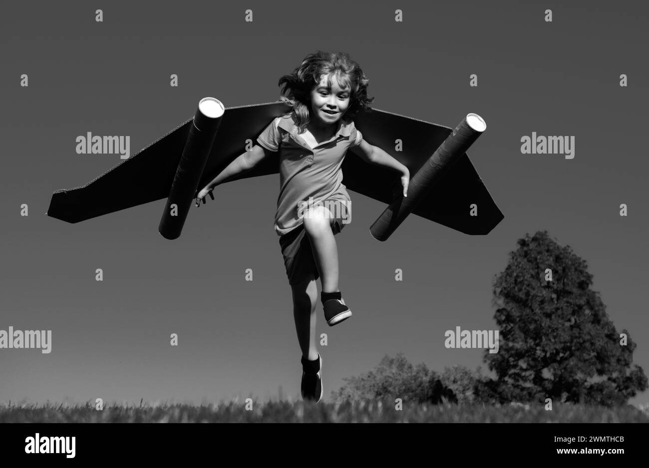 Happy child running with paper wings jumping against blue sky. Portrait ...