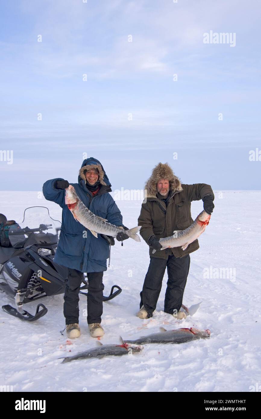 Steven kazlowski and Tim Cook guide ice fishing for sheefish on Kotzebue sound outside the village town of Kotzebue Sound Northwestern arctic Alaska Stock Photo