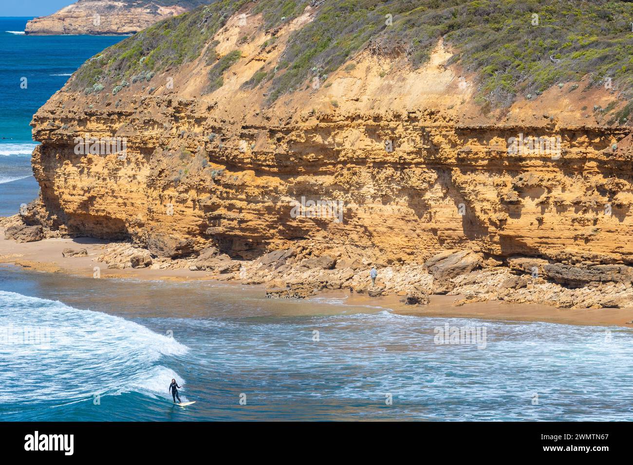 Surfers and the rugged coastline of Bells Beach in Victoria, Australia, seen from Winkipop on the Great Ocean Road. Stock Photo