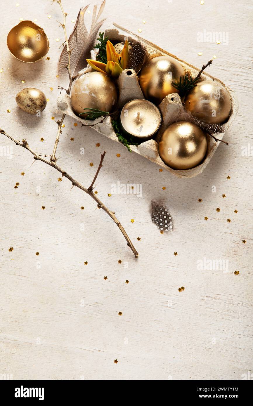 Stylish golden eggs easter concept. Easter gold eggs with flowers on light background. Happy easter card. Top view. Copy space. Stock Photo