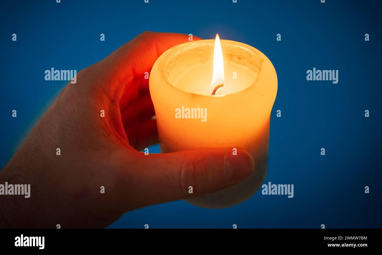 A hand holds a candle in the dark Stock Photo