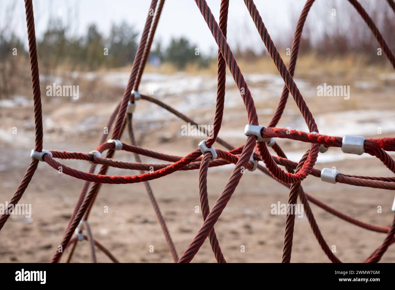Red rope sections fastened with a metal clamp and a brown sand background Stock Photo