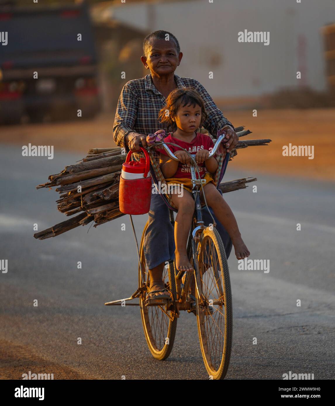 Grandma takes her Granddaughter from working with wood for cooking at Skun, Kampong Cham Stock Photo