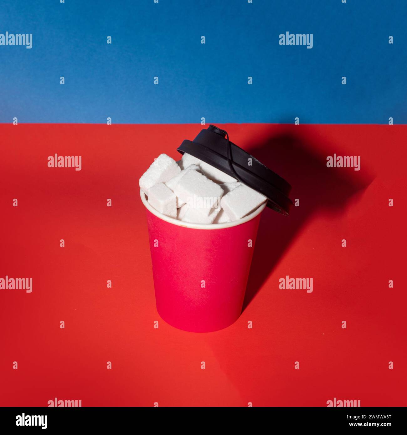 Disposable coffee cup and sugar cubes. Creative food concept. Copy space. Stock Photo